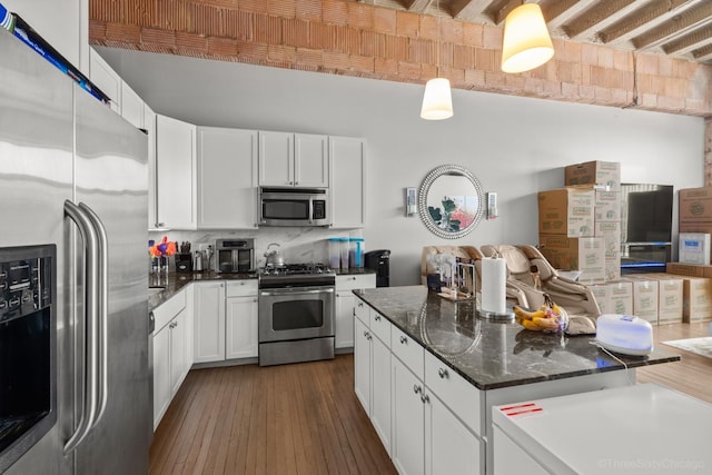 2545 S Dearborn St Unit 405, Chicago, IL 60616 - kitchen featuring stainless steel appliances, white cabinetry, open floor plan, and dark stone countertops