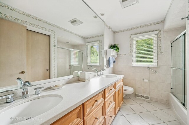 2620 Marian Ln, Wilmette, IL 60091 - bathroom featuring tile patterned floors, double vanity, tile walls, and shower / bath combination with glass door