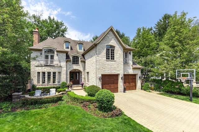 655 Thornwood Dr, Naperville, IL 60540 - french country home featuring stone siding, a balcony, french doors, a chimney, and an attached garage