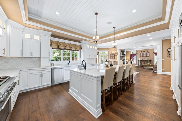 655 Thornwood Dr, Naperville, IL 60540 - kitchen featuring a tray ceiling, appliances with stainless steel finishes, ornamental molding, a center island with sink, and tasteful backsplash