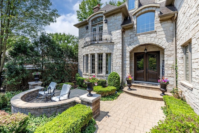 655 Thornwood Dr, Naperville, IL 60540 - entrance to property with a balcony, french doors, stone siding, a patio, and a chimney