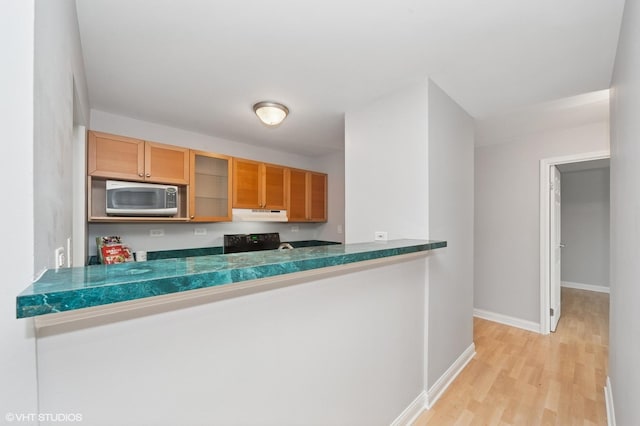 5600 Astor Ln Unit 301, Rolling Meadows, IL 60008 - kitchen with stainless steel microwave, ventilation hood, stove, glass insert cabinets, and light wood-style floors