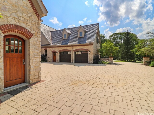 273 Donlea Rd, Barrington Hills, IL 60010 - view of side of home featuring stone siding, a high end roof, curved driveway, and a garage