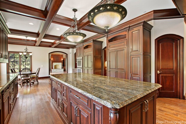 273 Donlea Rd, Barrington Hills, IL 60010 - kitchen featuring arched walkways, beam ceiling, light wood-style floors, a kitchen island, and dark stone countertops