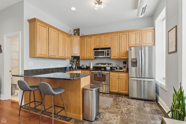 2212 N Campbell Ave Unit 1D, Chicago, IL 60647 - kitchen with stainless steel appliances, a peninsula, baseboards, a kitchen bar, and dark stone countertops