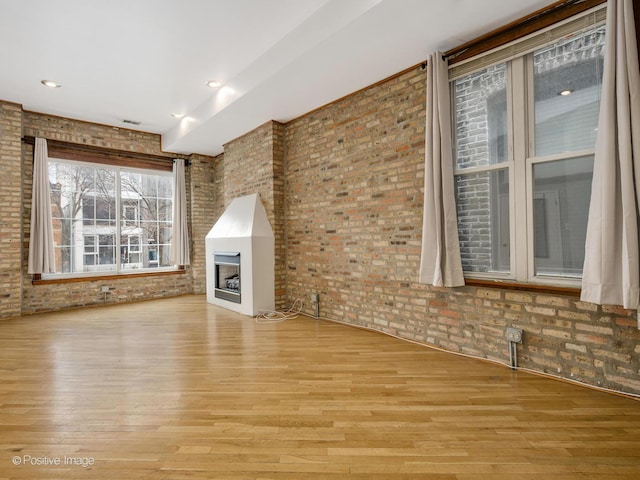 2023 W Armitage Ave, Chicago, IL 60647 - unfurnished living room featuring light wood finished floors, a fireplace, and brick wall