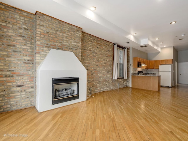 2023 W Armitage Ave, Chicago, IL 60647 - unfurnished living room featuring light wood-type flooring, brick wall, and a fireplace