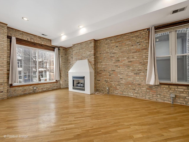 2023 W Armitage Ave, Chicago, IL 60647 - unfurnished living room with light wood-style flooring, a large fireplace, and brick wall