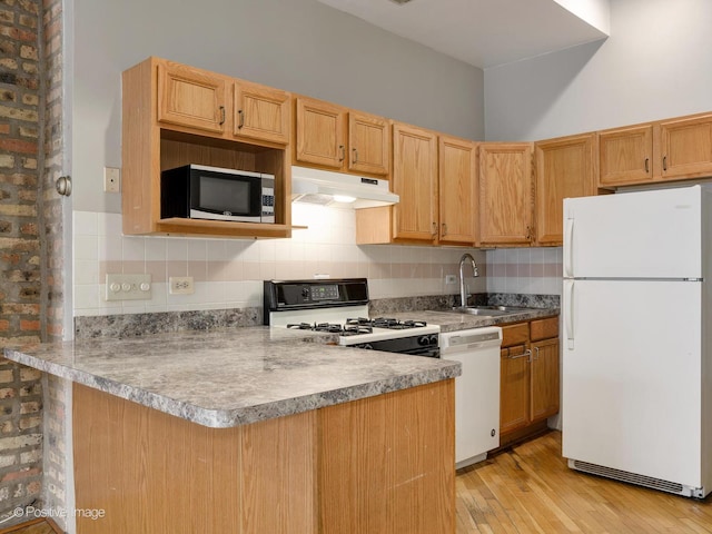 2023 W Armitage Ave, Chicago, IL 60647 - kitchen featuring white appliances, under cabinet range hood, a peninsula, light wood finished floors, and tasteful backsplash