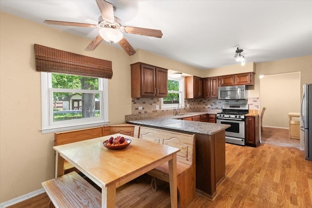 391 Northgate Rd, Lindenhurst, IL 60046 - kitchen with stainless steel appliances, a peninsula, backsplash, light wood-style floors, and baseboards