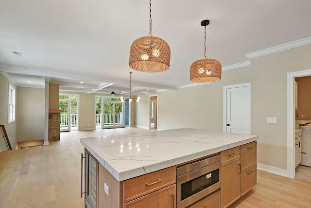 571 Mill St Unit 2, Fontana, WI 53125 - kitchen with stainless steel microwave, light wood-style flooring, open floor plan, ornamental molding, and a center island