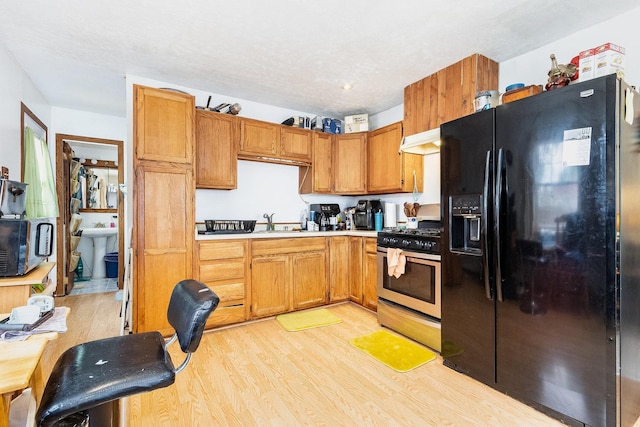 431 Montrose Dr, Romeoville, IL 60446 - kitchen with black fridge, stainless steel gas stove, light wood-type flooring, a sink, and light countertops