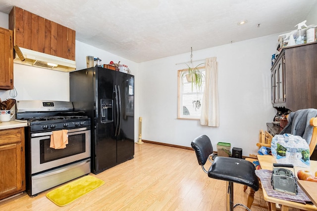431 Montrose Dr, Romeoville, IL 60446 - kitchen with under cabinet range hood, stainless steel gas range, black fridge, light wood-type flooring, and light countertops
