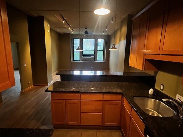600 S Dearborn St Unit 308, Chicago, IL 60605 - kitchen featuring track lighting, a peninsula, a sink, brown cabinetry, and dark stone counters