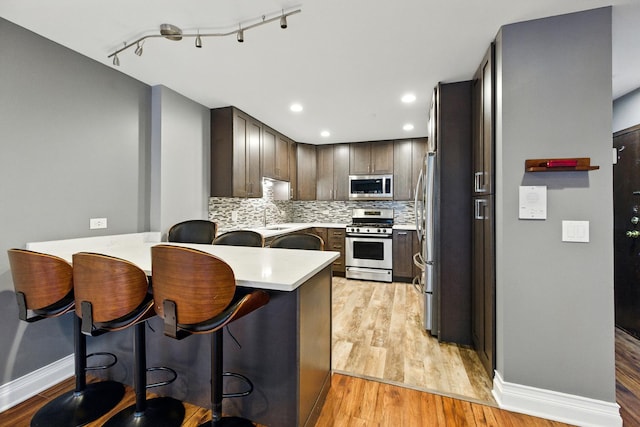 1258 Brown St Unit 204, Des Plaines, IL 60016 - kitchen featuring stainless steel appliances, a peninsula, light countertops, light wood-style flooring, and recessed lighting