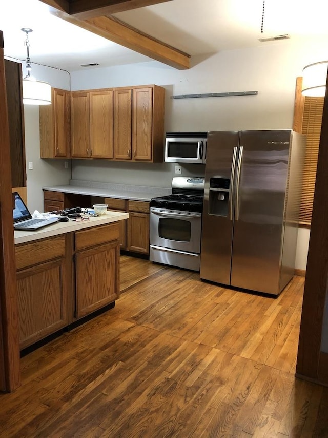 1252 W Chicago Ave, Chicago, IL 60642 - kitchen featuring appliances with stainless steel finishes, light countertops, brown cabinetry, wood finished floors, and beam ceiling
