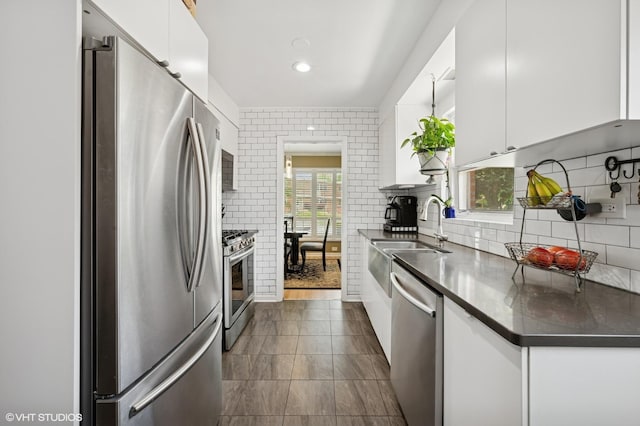9519 Kolmar Ave, Skokie, IL 60076 - kitchen with stainless steel appliances, a sink, white cabinets, dark countertops, and tasteful backsplash