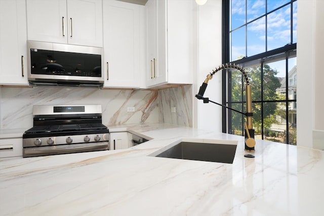 4153 N Hermitage Ave, Chicago, IL 60613 - kitchen with appliances with stainless steel finishes, white cabinetry, tasteful backsplash, and light stone counters
