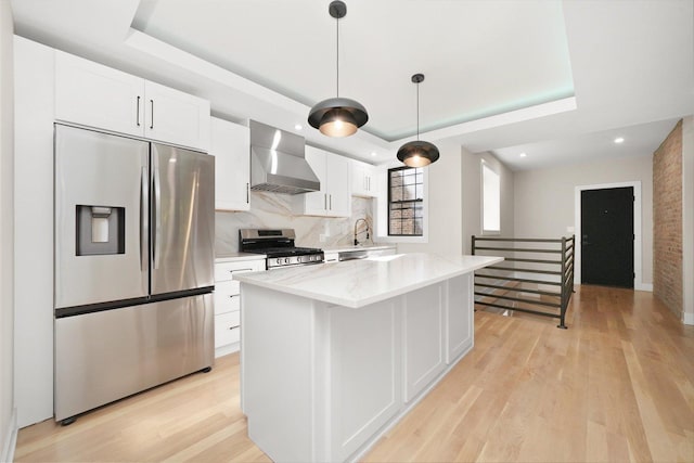 4153 N Hermitage Ave, Chicago, IL 60613 - kitchen with stainless steel appliances, wall chimney exhaust hood, a raised ceiling, light wood finished floors, and white cabinetry