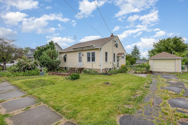 424 Robinson St, Earlville, IL 60518 - view of front of property featuring an outdoor structure, a garage, a front yard, a chimney, and a shingled roof