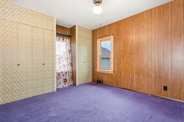 424 Robinson St, Earlville, IL 60518 - unfurnished bedroom featuring carpet, wooden walls, ceiling fan, and a closet