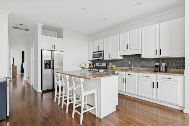 1632 W Erie St Unit 3, Chicago, IL 60622 - kitchen with appliances with stainless steel finishes, a breakfast bar, dark wood finished floors, light stone countertops, and a kitchen island