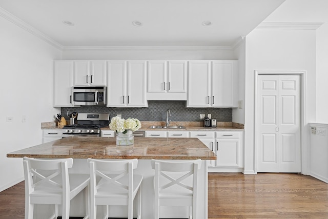 1632 W Erie St Unit 3, Chicago, IL 60622 - kitchen featuring stainless steel appliances, white cabinets, light wood-style floors, and ornamental molding