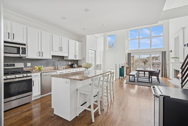 1632 W Erie St Unit 3, Chicago, IL 60622 - kitchen with stainless steel appliances, dark wood-style floors, a breakfast bar area, a kitchen island, and tasteful backsplash