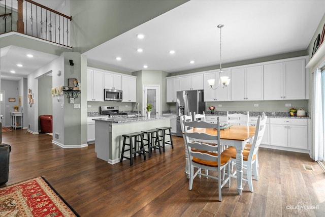 1285 Highpoint Ct, Bartlett, IL 60103 - kitchen featuring stainless steel appliances, a kitchen island with sink, dark wood-type flooring, white cabinetry, and a breakfast bar area