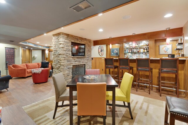 10415 Ridge Ln, Huntley, IL 60142 - dining room with light wood-style floors, a stone fireplace, recessed lighting, and a community bar
