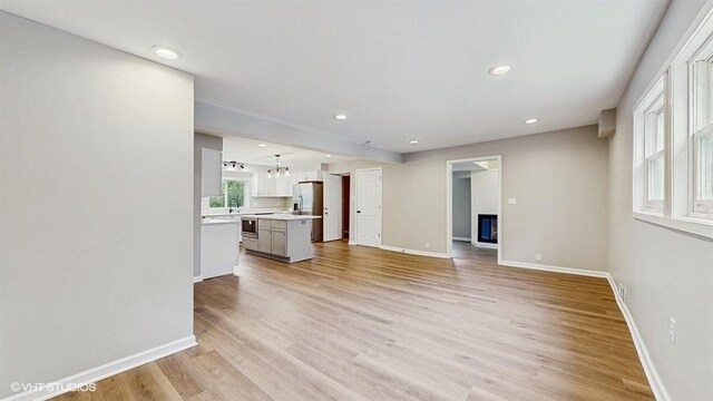 4622 Schwartz Ave, Lisle, IL 60532 - unfurnished living room featuring light wood-style floors, baseboards, recessed lighting, a glass covered fireplace, and a sink