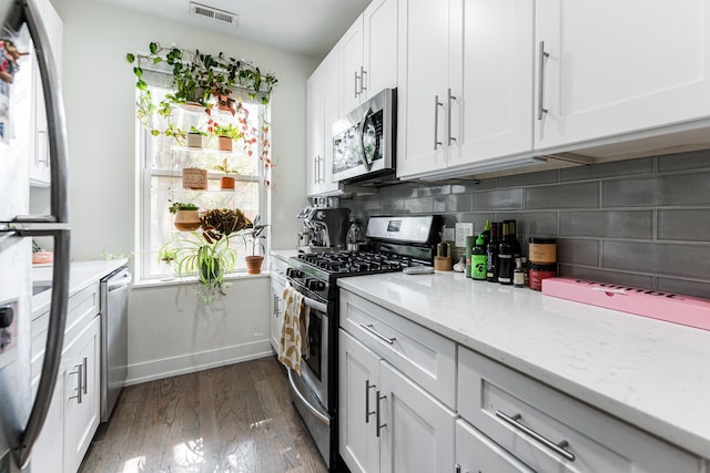 1407 N Bosworth Ave, Chicago, IL 60642 - kitchen with appliances with stainless steel finishes, backsplash, dark wood-style floors, white cabinets, and light stone counters