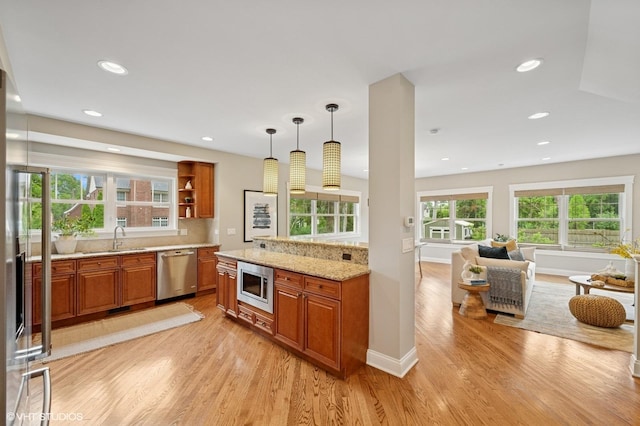 234 E Saint Charles Rd, Elmhurst, IL 60126 - kitchen with stainless steel appliances, brown cabinetry, light wood finished floors, light stone countertops, and decorative light fixtures