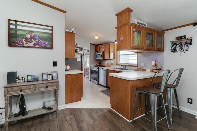 103 S Benson St, Lexington, IL 61753 - kitchen with a peninsula, brown cabinets, stainless steel appliances, glass insert cabinets, and light countertops