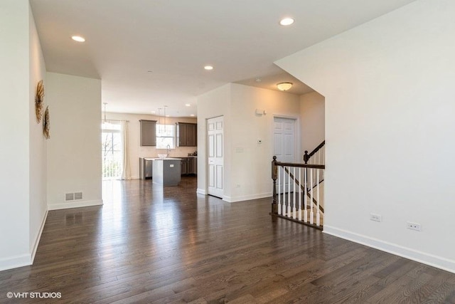 1425 N Charles Ave, Naperville, IL 60563 - unfurnished living room featuring dark wood-type flooring, baseboards, recessed lighting, a sink, and stairs