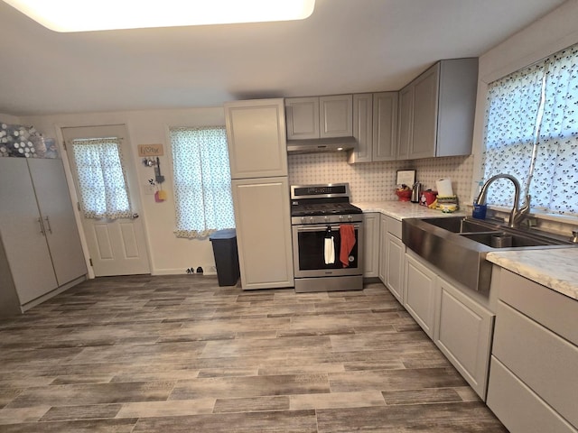108 E Washington St, Ashkum, IL 60911 - kitchen featuring stainless steel range with gas cooktop, under cabinet range hood, gray cabinets, light countertops, and a sink