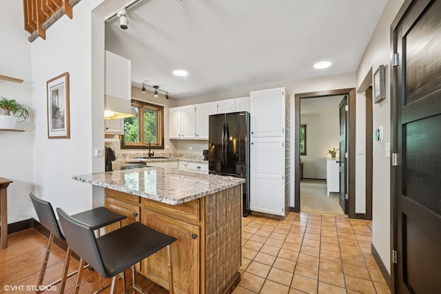 11214 Halma Ln, Woodstock, IL 60098 - kitchen with freestanding refrigerator, track lighting, white cabinetry, a kitchen breakfast bar, and light stone counters