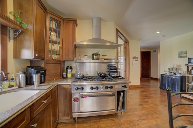 1897 N 2500 E Rd, Watseka, IL 60970 - kitchen featuring wall chimney exhaust hood, high end stove, brown cabinets, wood finished floors, and glass insert cabinets