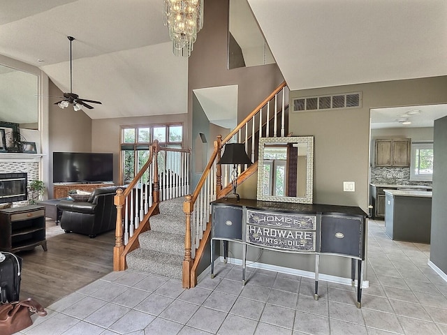23243 S Volbrecht Rd, Crete, IL 60417 - staircase featuring tile patterned flooring, ceiling fan, high vaulted ceiling, a chandelier, and a glass covered fireplace