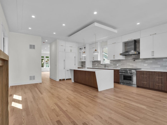 4845 N Mcvicker Ave, Chicago, IL 60630 - kitchen featuring wall chimney range hood, stainless steel stove, modern cabinets, light wood-style flooring, and white cabinets