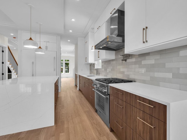 4845 N Mcvicker Ave, Chicago, IL 60630 - kitchen with stainless steel stove, modern cabinets, wall chimney exhaust hood, light wood-style floors, and white cabinetry