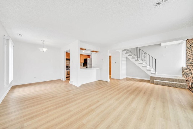 9830 Sayre Ave Unit 7, Chicago Ridge, IL 60415 - unfurnished living room with a textured ceiling, light wood-style flooring, stairs, and baseboards