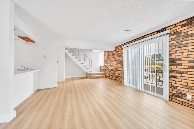 9830 Sayre Ave Unit 7, Chicago Ridge, IL 60415 - unfurnished living room featuring brick wall, wood finished floors, healthy amount of natural light, a textured ceiling, and stairs