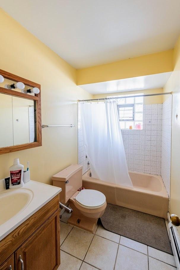 1619 N 35th Ave, Melrose Park, IL 60160 - bathroom featuring baseboard heating, vanity, shower / bath combination with curtain, toilet, and tile patterned flooring