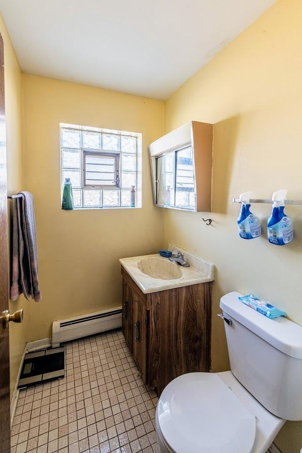 1619 N 35th Ave, Melrose Park, IL 60160 - half bathroom featuring a baseboard radiator, toilet, vanity, and tile patterned floors