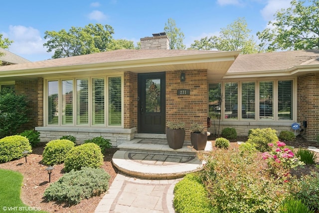 231 N Forest Ct, Addison, IL 60101 - view of exterior entry with brick siding, a chimney, and a porch