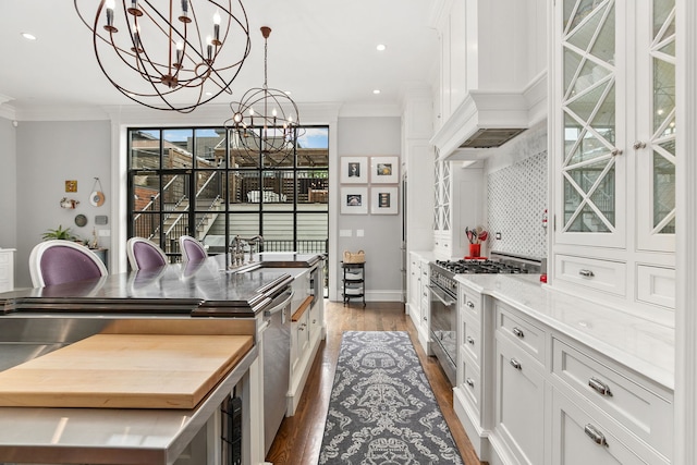2429 W Belden Ave, Chicago, IL 60647 - kitchen with stainless steel appliances, ornamental molding, a chandelier, wood finished floors, and white cabinetry