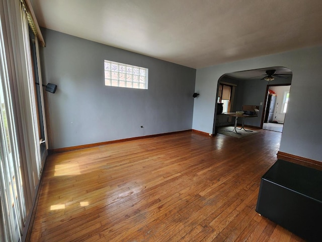 7112 W Farragut Ave, Chicago, IL 60656 - unfurnished living room with arched walkways, a ceiling fan, healthy amount of natural light, and hardwood / wood-style flooring