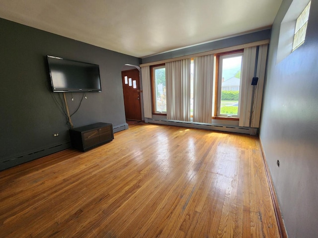 7112 W Farragut Ave, Chicago, IL 60656 - unfurnished living room featuring arched walkways, wood finished floors, and a baseboard radiator