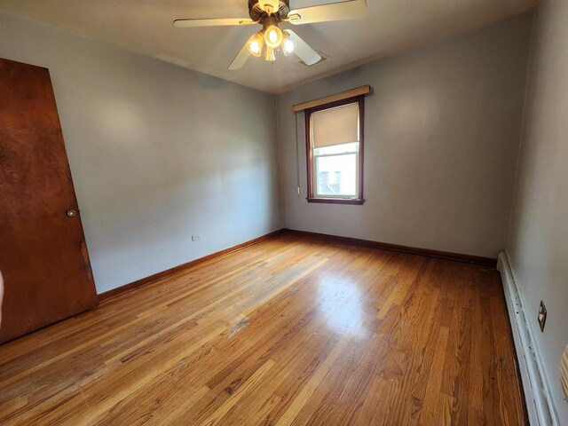 7112 W Farragut Ave, Chicago, IL 60656 - spare room with wood finished floors, ceiling fan, a baseboard heating unit, and baseboards